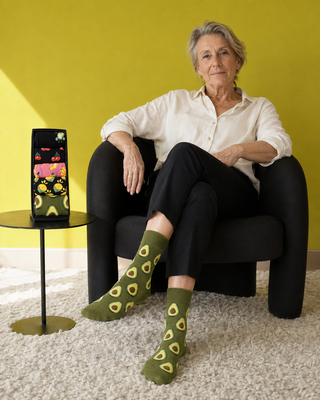 Une femme porte des chaussettes avocat à côté de son coffret Pairelipopette